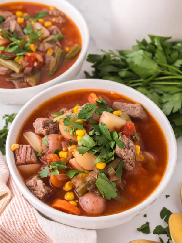 slow cooker beef veggie soup in white serving bowls.