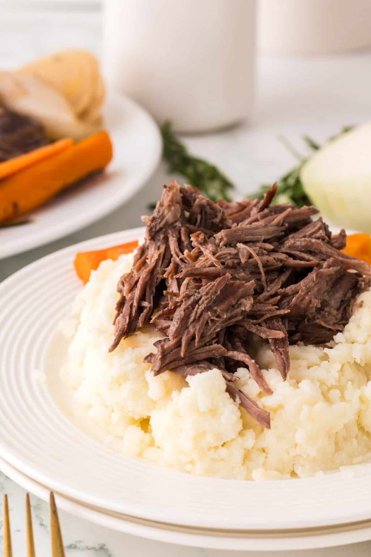 slow cooker pot roast dinner on a round white plate.