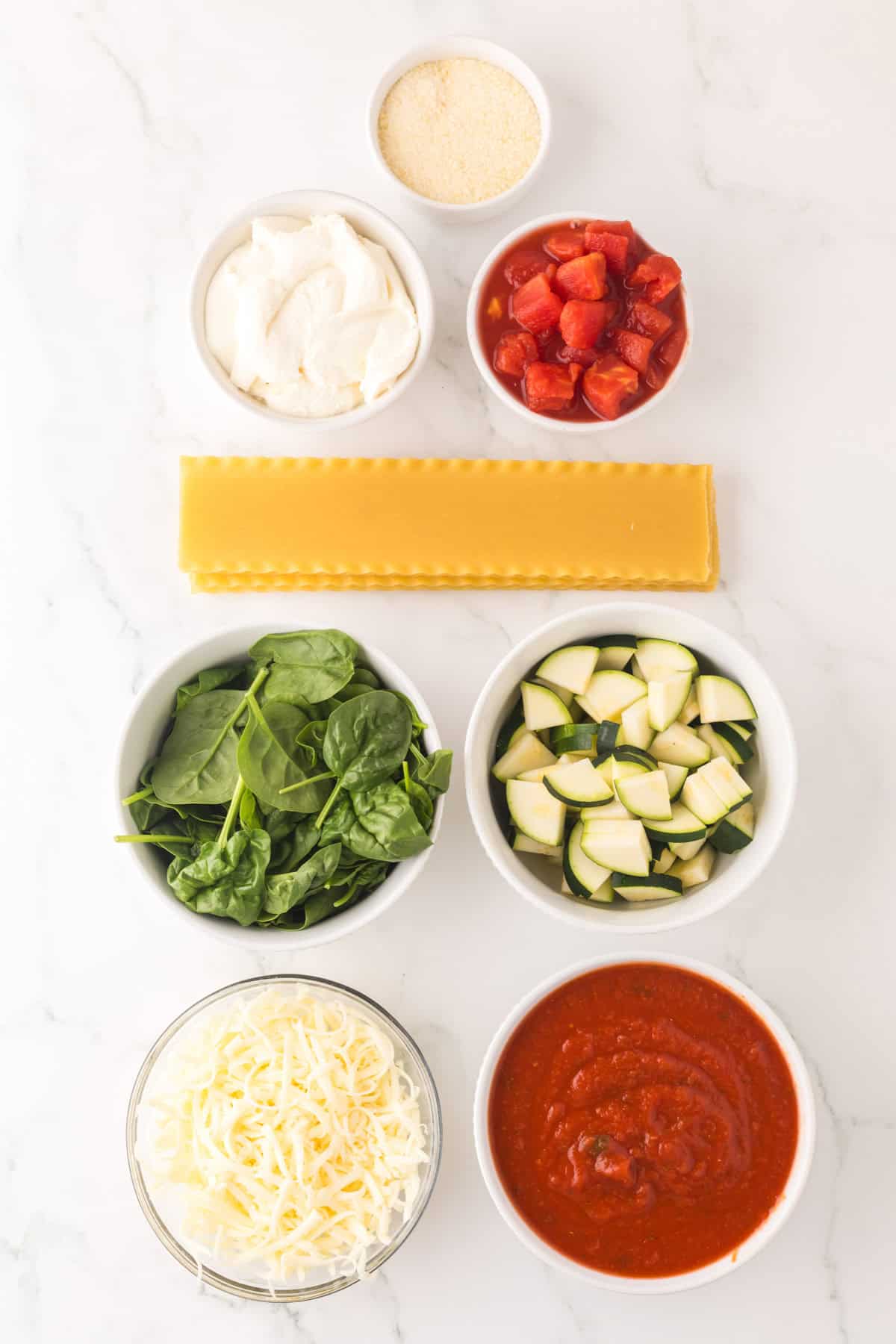 portion bowls each with raw ingredients to make slow cooker veggie lasagna.