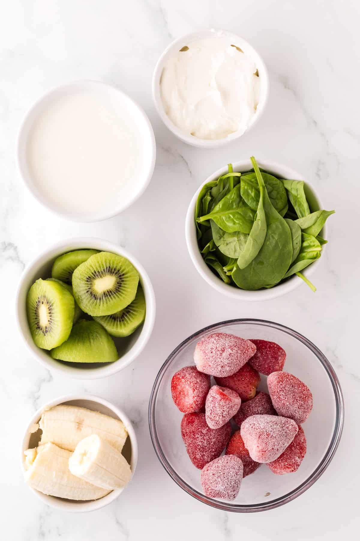 portion bowls each with raw ingredients to make strawberry kiwi smoothies.