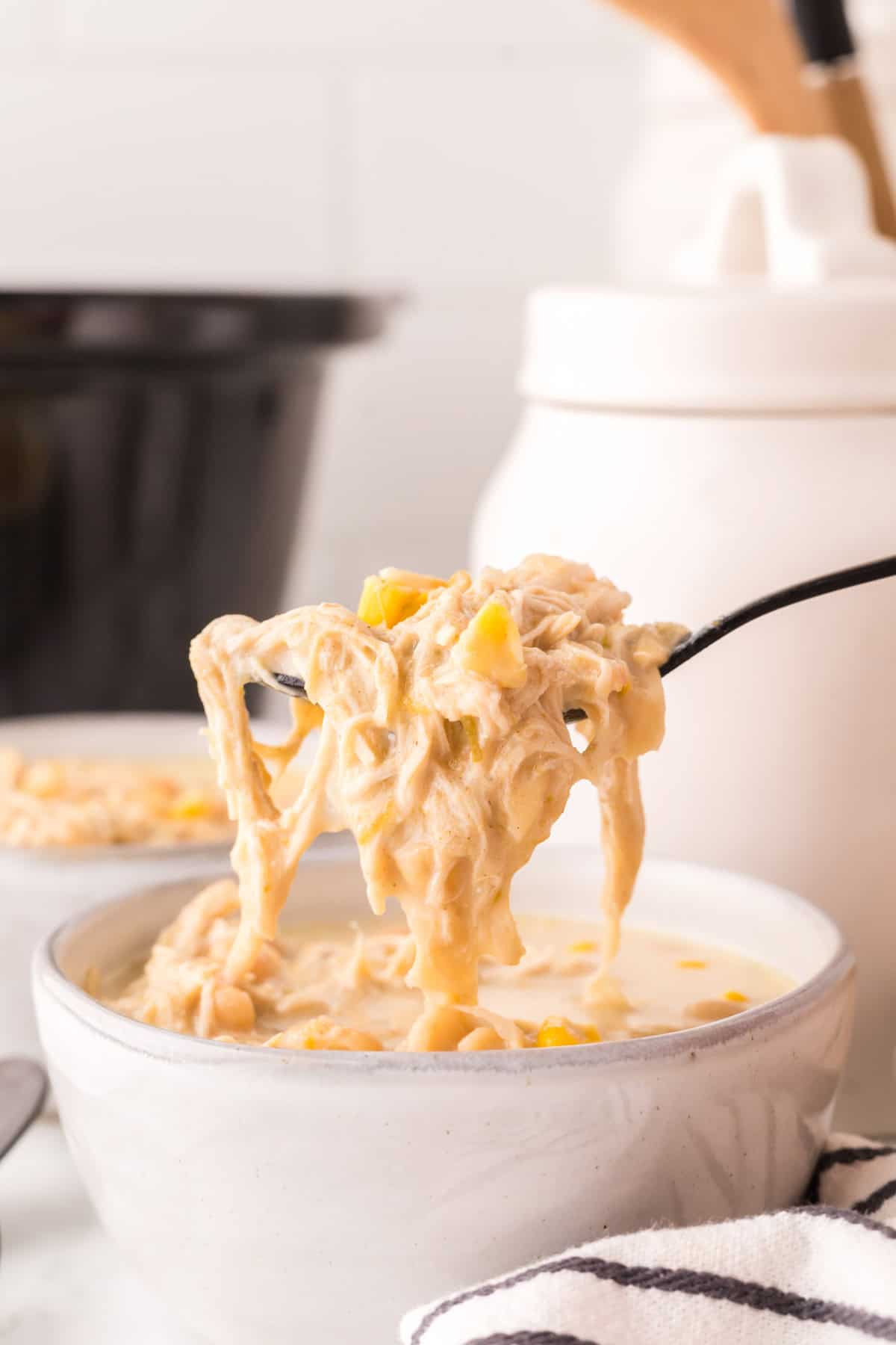 spoonful of white chicken chili in white serving bowls.