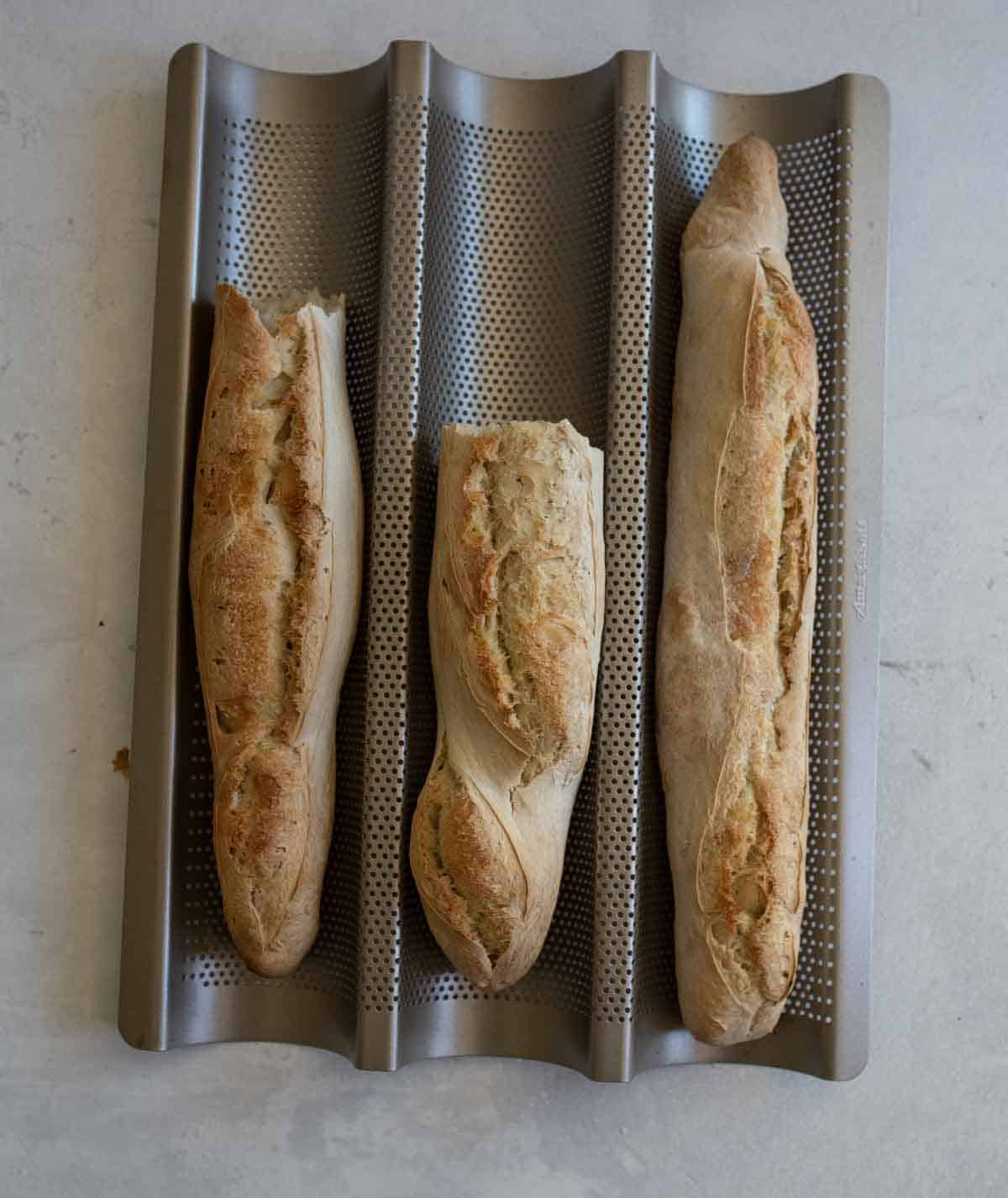 three baked baguettes in metal baguette pan.