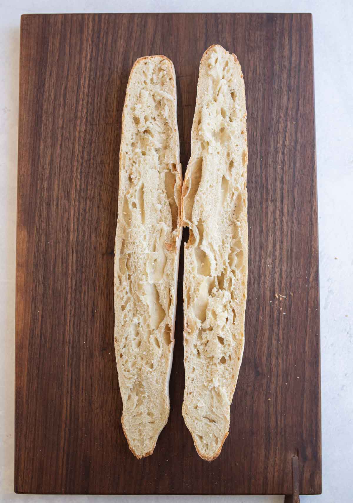 sourdough baguette sliced open on brown board.