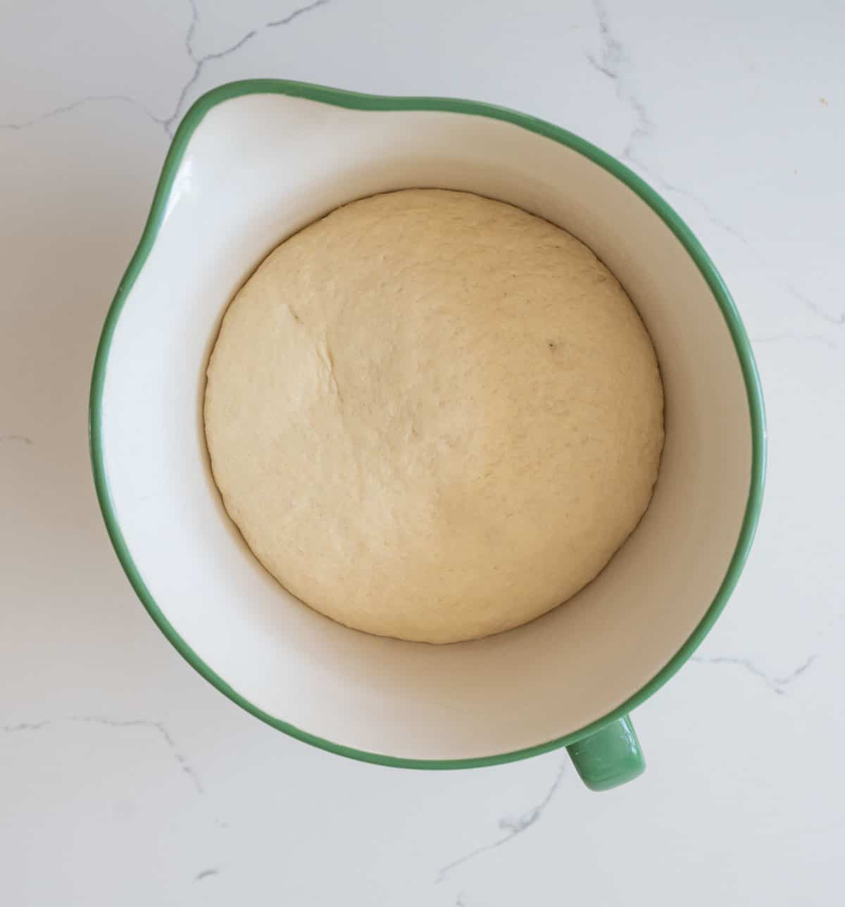 overhead view of dough rising in white and blue bowl.