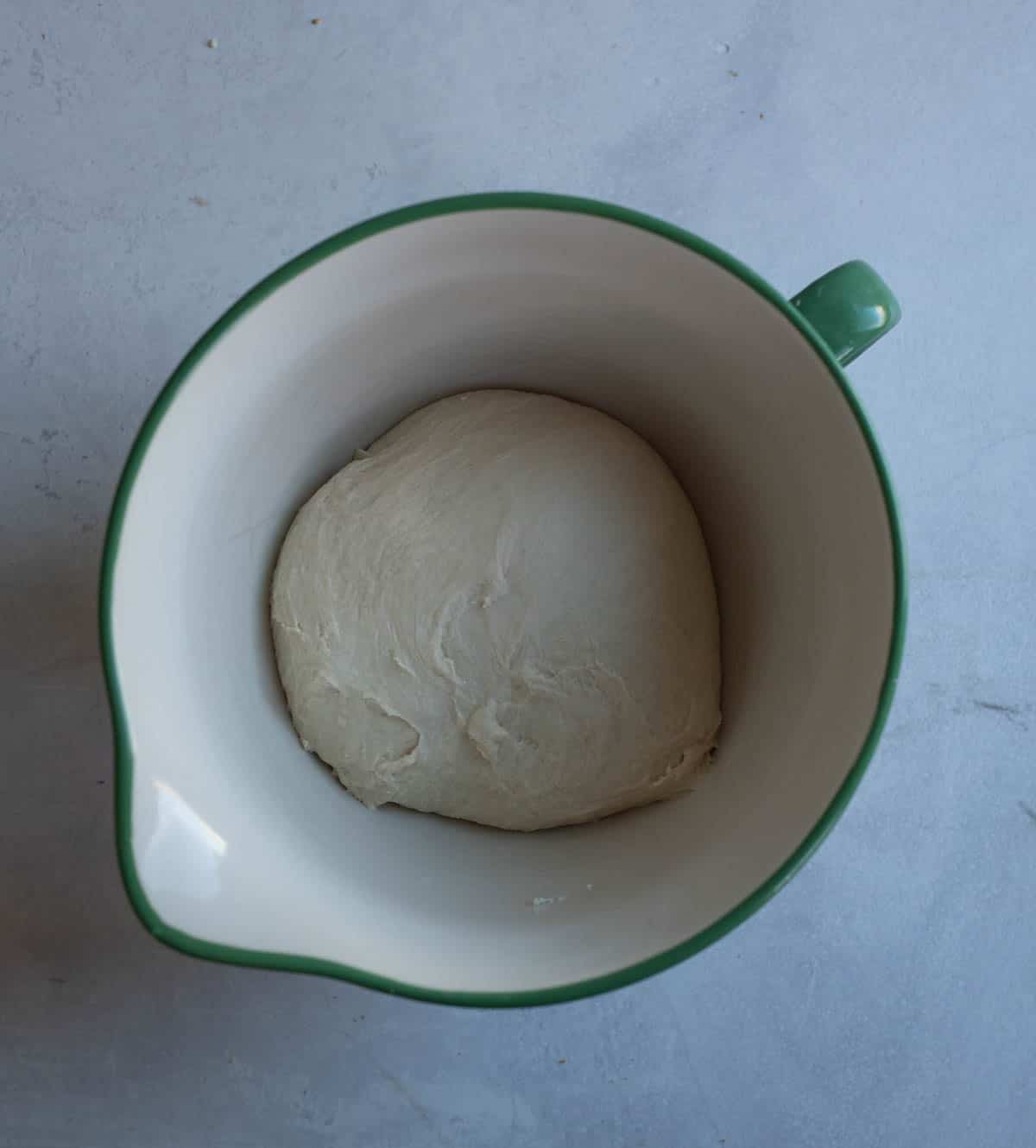 overhead view of dough in white and blue bowl.