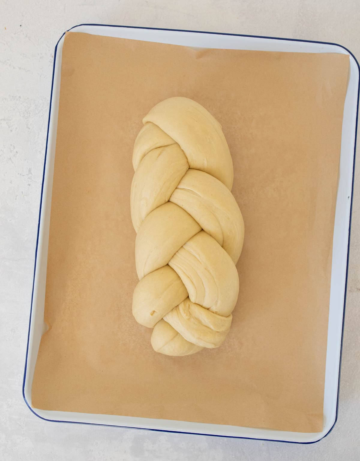 braided sourdough challah bread dough on white sheet pan.