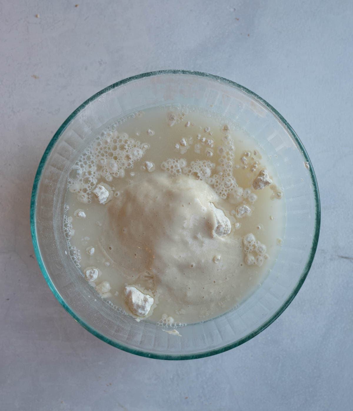 sourdough english muffin ingredients in clear glass bowl.