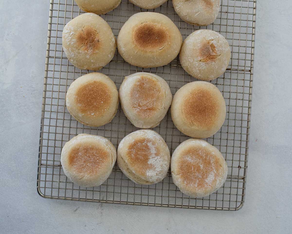 baked sourdough english muffins on metal wire cooling rack.