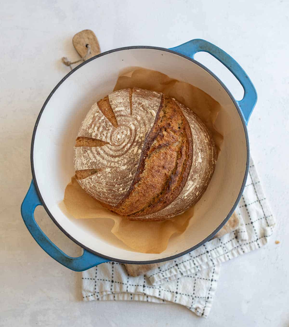 baked round rye bread loaf in blue dutch oven.