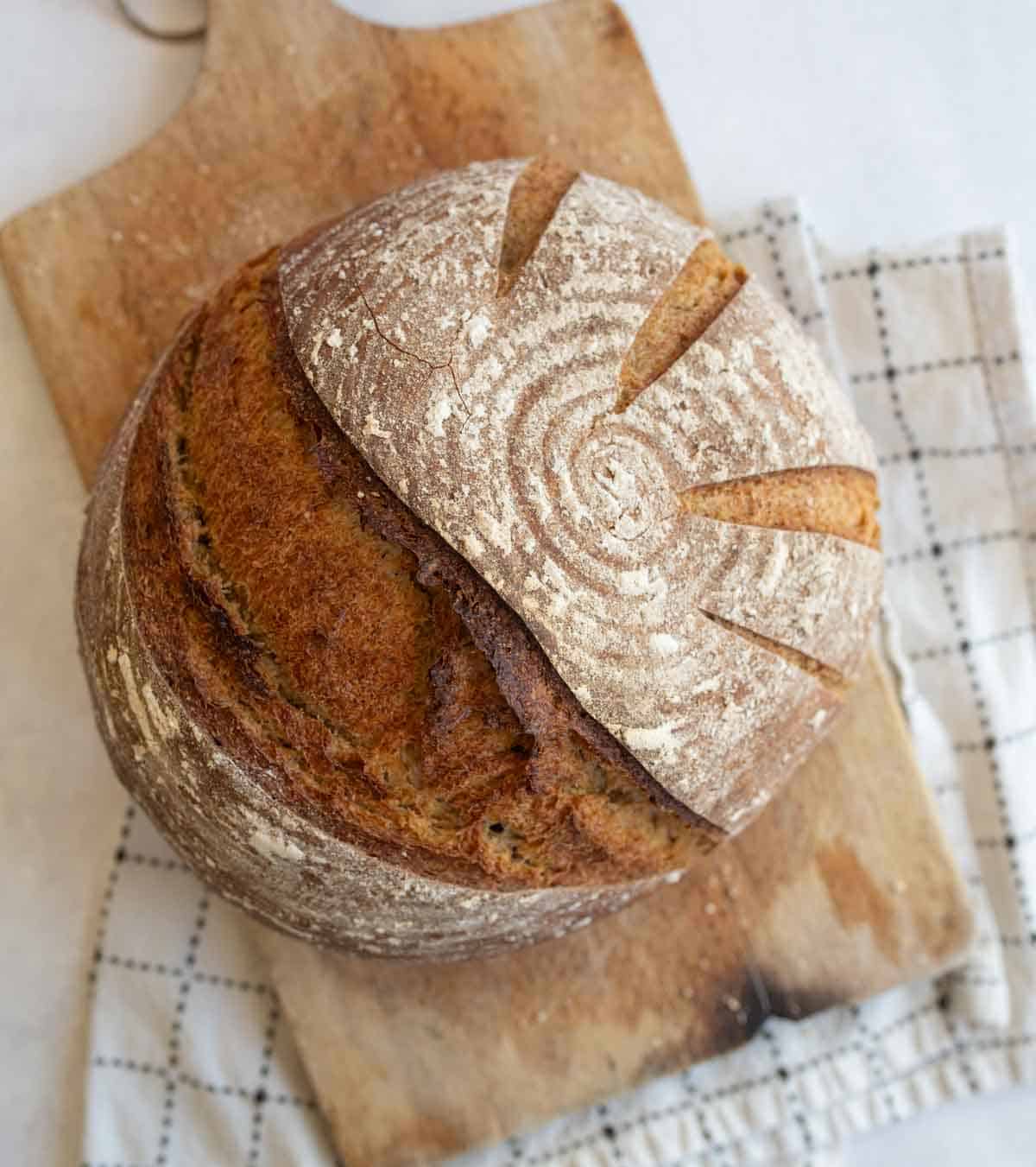 round loaf of sourdough rye bread on brown wooden board.