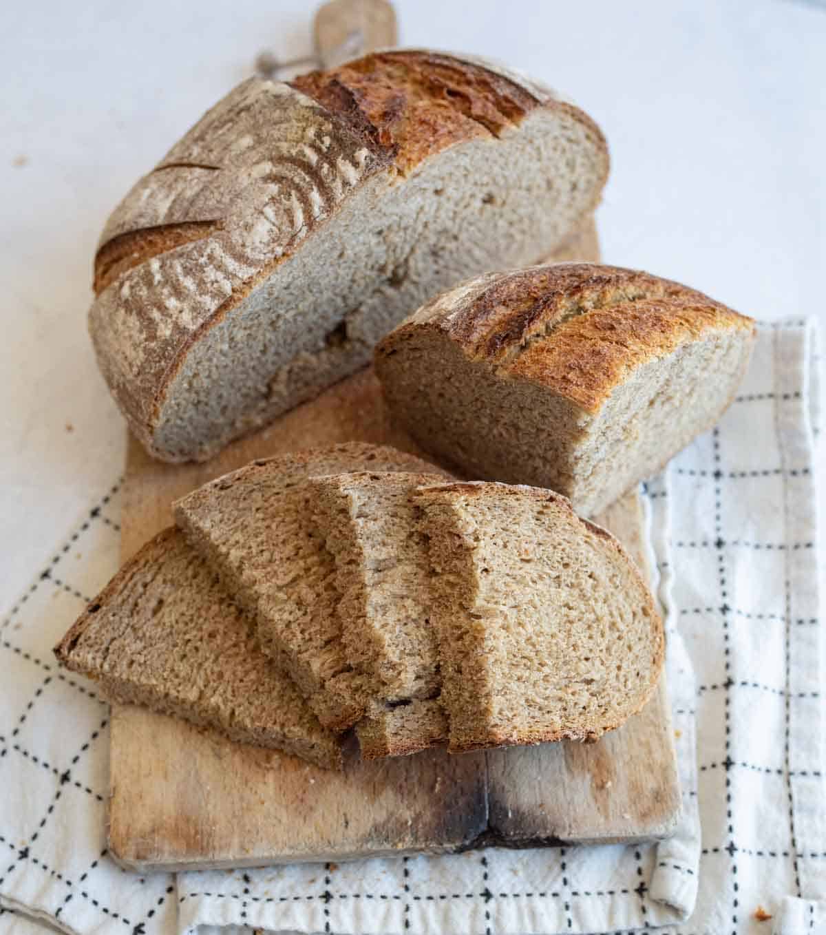 round loaf of rye bread cut up on towel.