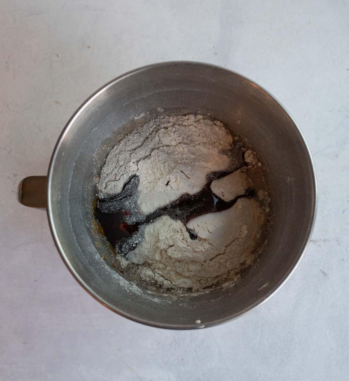 ingredients for rye bread in mixer bowl on white countertop.