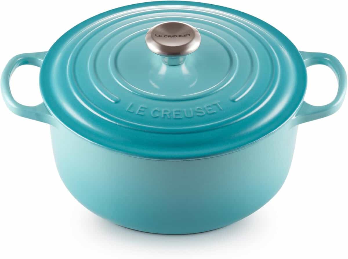 A bright turquoise Le Creuset Dutch oven with a lid and two handles. The lid features the brand logo and a silver knob at the center. The pots enamel finish gives it a sleek and shiny appearance.