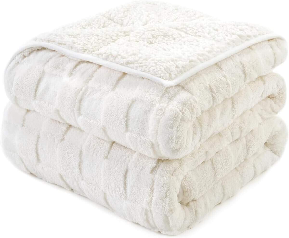 A neatly folded, soft, cream-colored plush blanket with a quilted design. The fabric appears thick and fluffy, ideal for warmth and comfort.