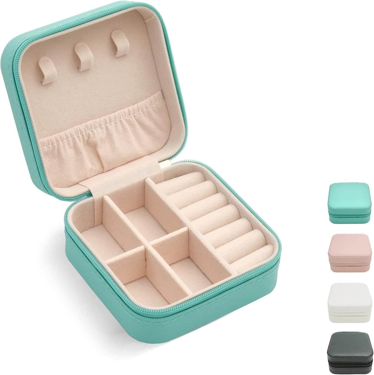 A turquoise square jewelry box with a zippered closure is open, revealing a soft beige interior. It features compartments for rings and earrings. Below are four smaller boxes in teal, pink, white, and black.