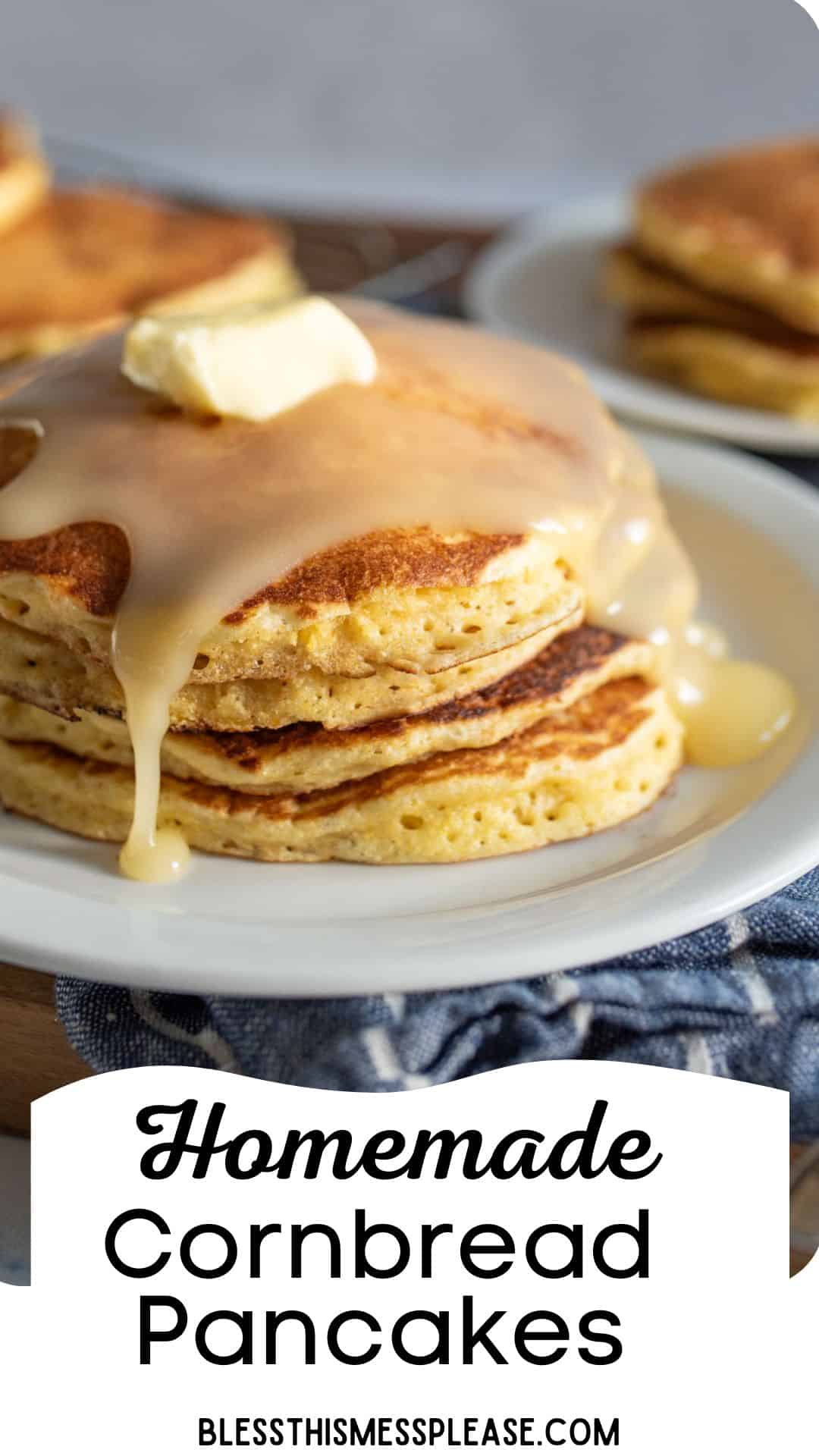 A stack of homemade cornbread pancakes topped with a pat of butter and drizzled with syrup on a white plate. Another plate with pancakes is in the background. A cloth napkin and the text Homemade Cornbread Pancakes and blessthismessplease.com are visible.