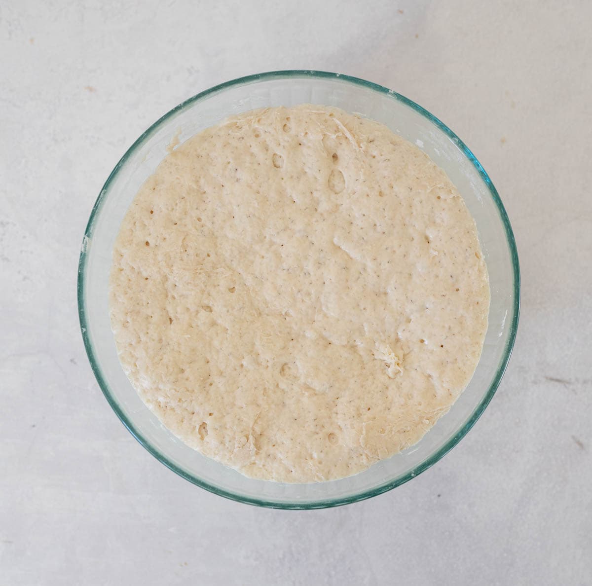 bubbly dough for sourdough cinnamon swirl bread in clear bowl.