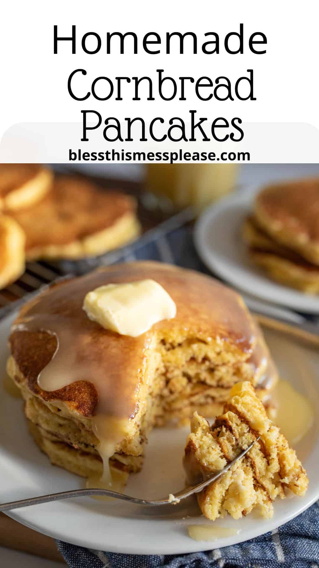 A stack of homemade cornbread pancakes topped with butter and syrup on a plate. A fork holds a bite-sized piece in the foreground. Another plate with pancakes is blurred in the background. Text above reads, Homemade Cornbread Pancakes.