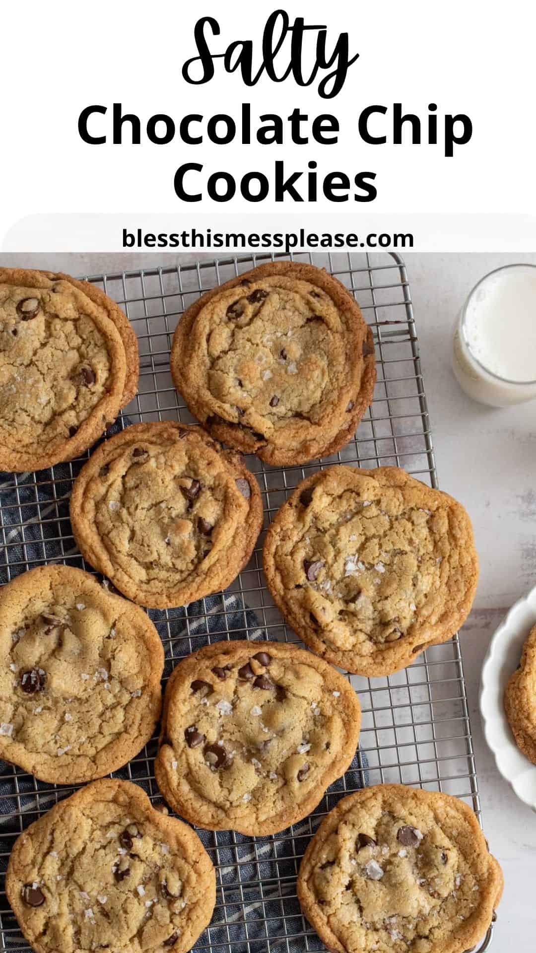 A tray of freshly baked chocolate chip cookies with a sprinkle of salt is placed on a wire rack. A glass of milk and a small plate with a cookie are beside it. Salty Chocolate Chip Cookies and blessthismessplease.com are written above.