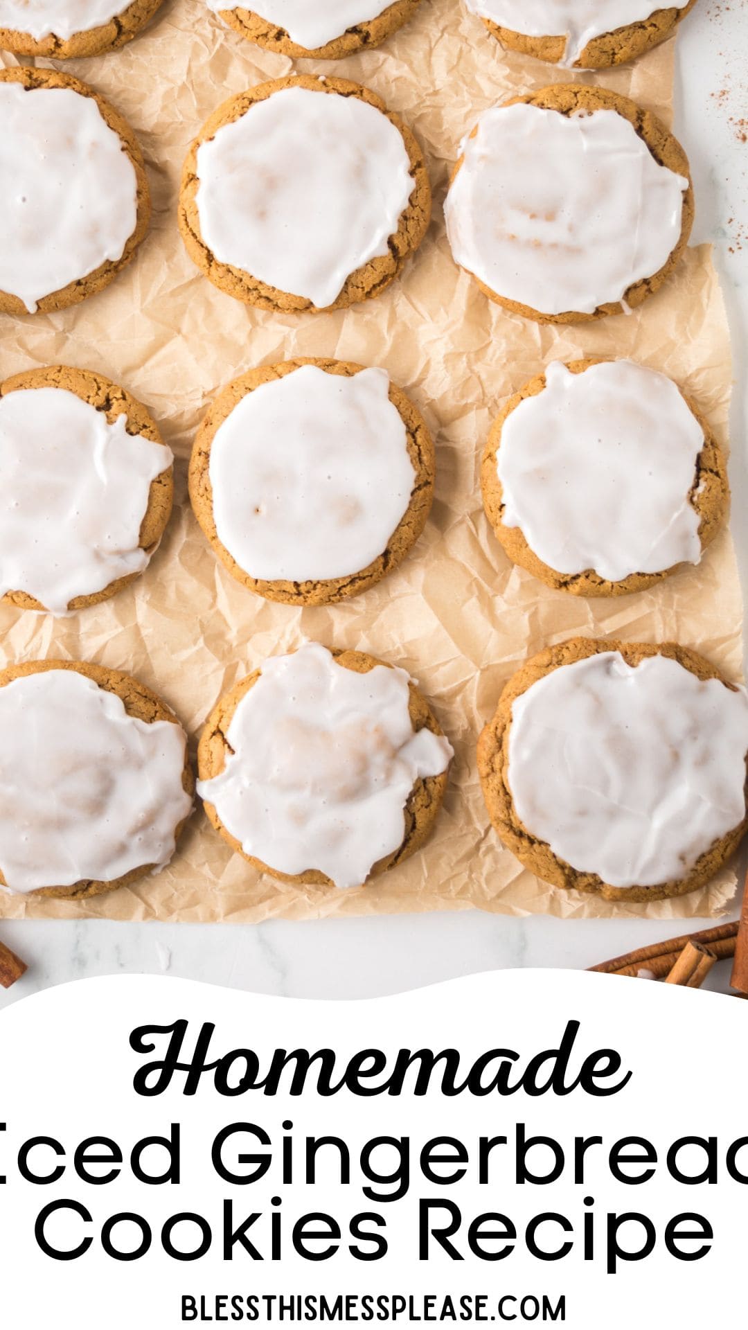 Top view of iced gingerbread cookies arranged on parchment paper. The cookies are decorated with white icing and a few cinnamon sticks are placed around them. A text overlay reads, Homemade Iced Gingerbread Cookies Recipe at the bottom.